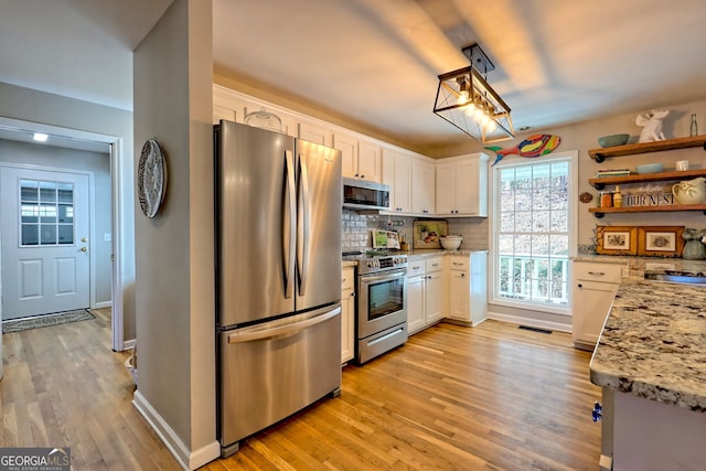 kitchen featuring white cabinetry, appliances with stainless steel finishes, light stone countertops, and light wood-type flooring