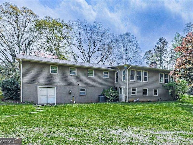 rear view of property with a lawn and central air condition unit