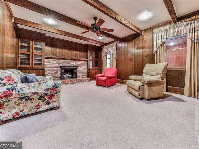 living room with a fireplace, wooden walls, carpet, ceiling fan, and beam ceiling