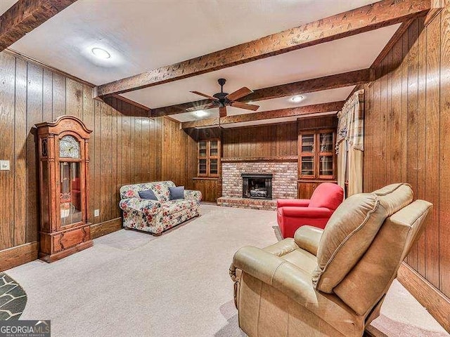 carpeted living room with a brick fireplace, wooden walls, and beamed ceiling