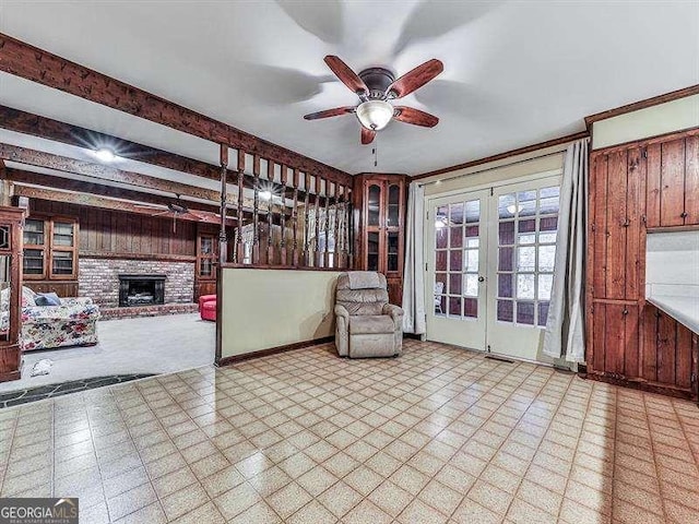 unfurnished room with french doors, ceiling fan, a fireplace, and beamed ceiling