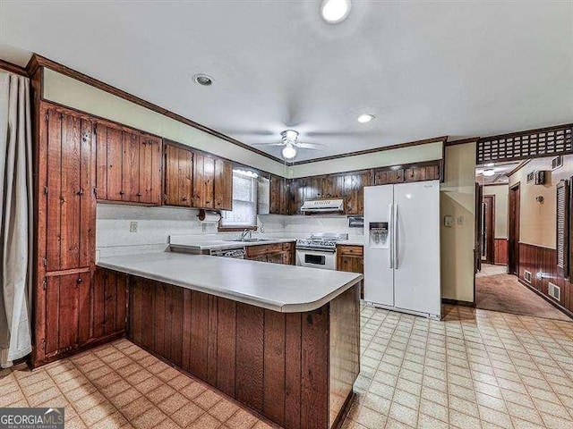 kitchen with sink, stainless steel range, kitchen peninsula, ceiling fan, and white refrigerator with ice dispenser