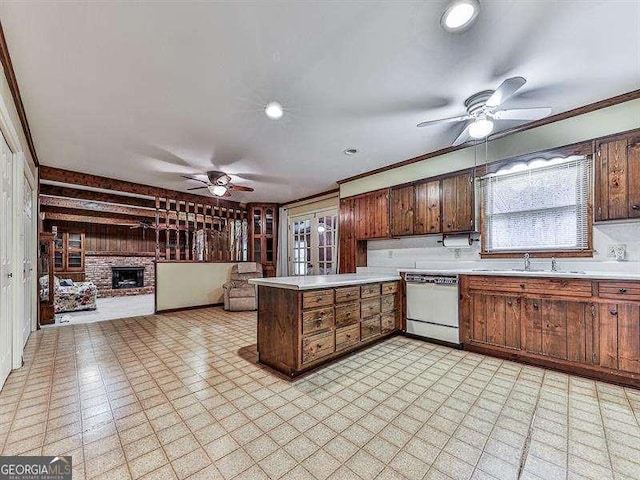 kitchen featuring sink, ceiling fan, dishwasher, a brick fireplace, and kitchen peninsula