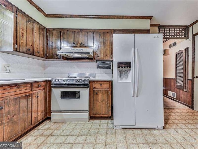 kitchen with white appliances, ornamental molding, sink, and wood walls