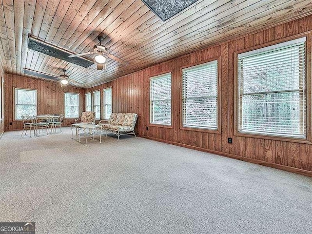 unfurnished room with ceiling fan, carpet, wood ceiling, and wood walls