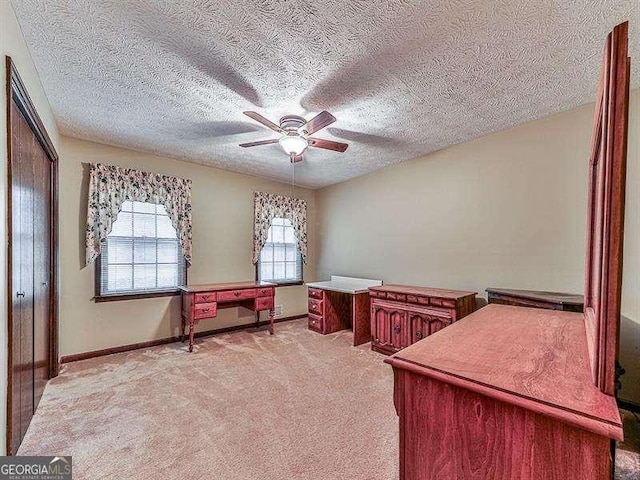 carpeted office featuring a textured ceiling and ceiling fan