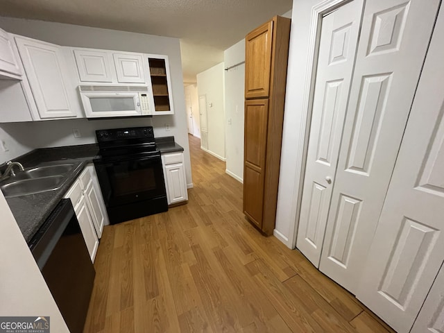 kitchen with white cabinetry, sink, light wood-type flooring, and black appliances