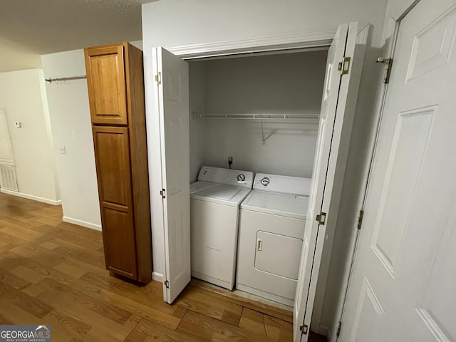 laundry area with light hardwood / wood-style floors, washer and dryer, and a textured ceiling