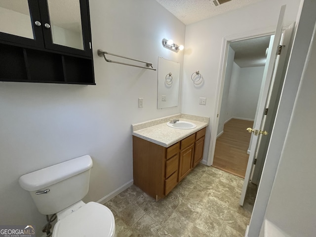 bathroom featuring vanity, toilet, and a textured ceiling