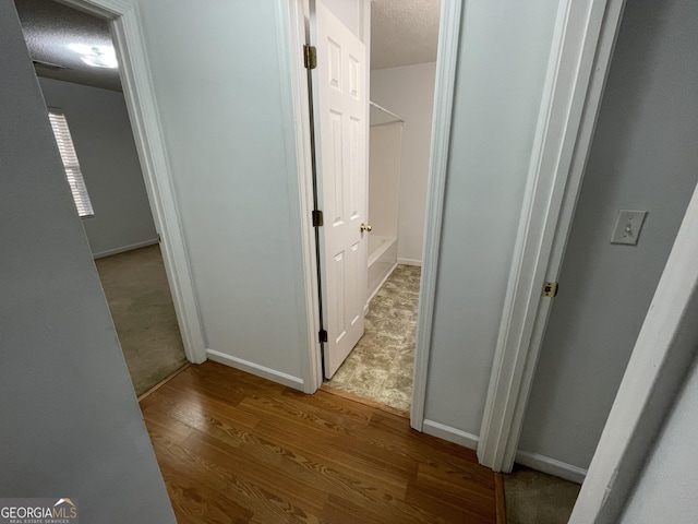 hallway with a textured ceiling and light wood-type flooring