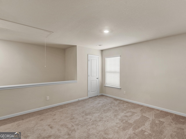 empty room with attic access, carpet, visible vents, and baseboards