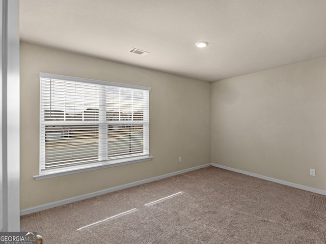 carpeted spare room with visible vents and baseboards