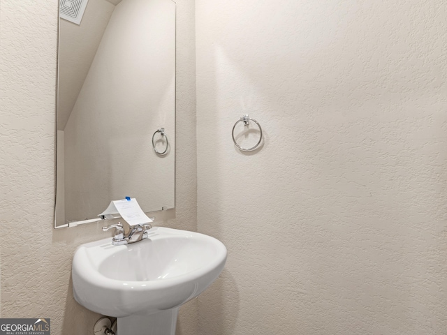 bathroom featuring visible vents, a sink, and a textured wall