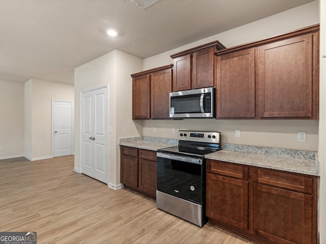 kitchen featuring light stone countertops, light wood finished floors, baseboards, and stainless steel appliances