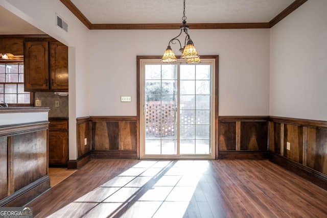 unfurnished dining area featuring an inviting chandelier, crown molding, and light hardwood / wood-style flooring