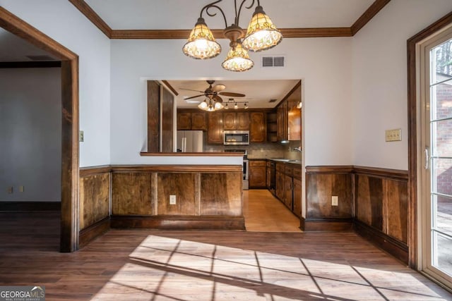 kitchen featuring light hardwood / wood-style flooring, ornamental molding, and appliances with stainless steel finishes