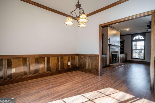 empty room featuring crown molding, ceiling fan with notable chandelier, and hardwood / wood-style flooring