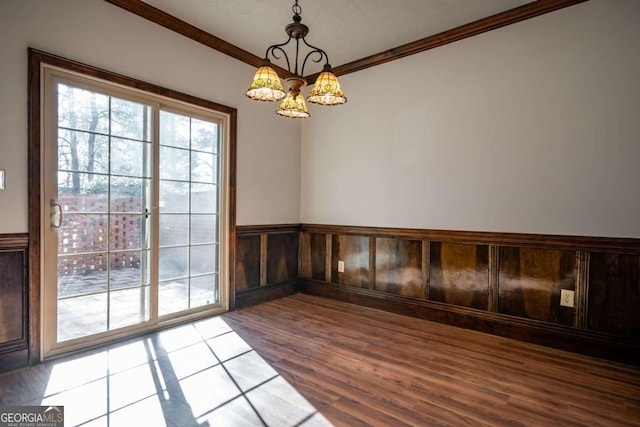 spare room featuring crown molding, wood-type flooring, and a notable chandelier