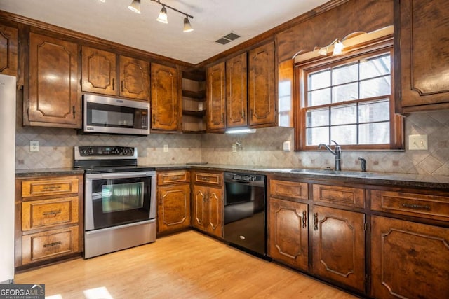 kitchen with stainless steel appliances, sink, backsplash, and light hardwood / wood-style flooring