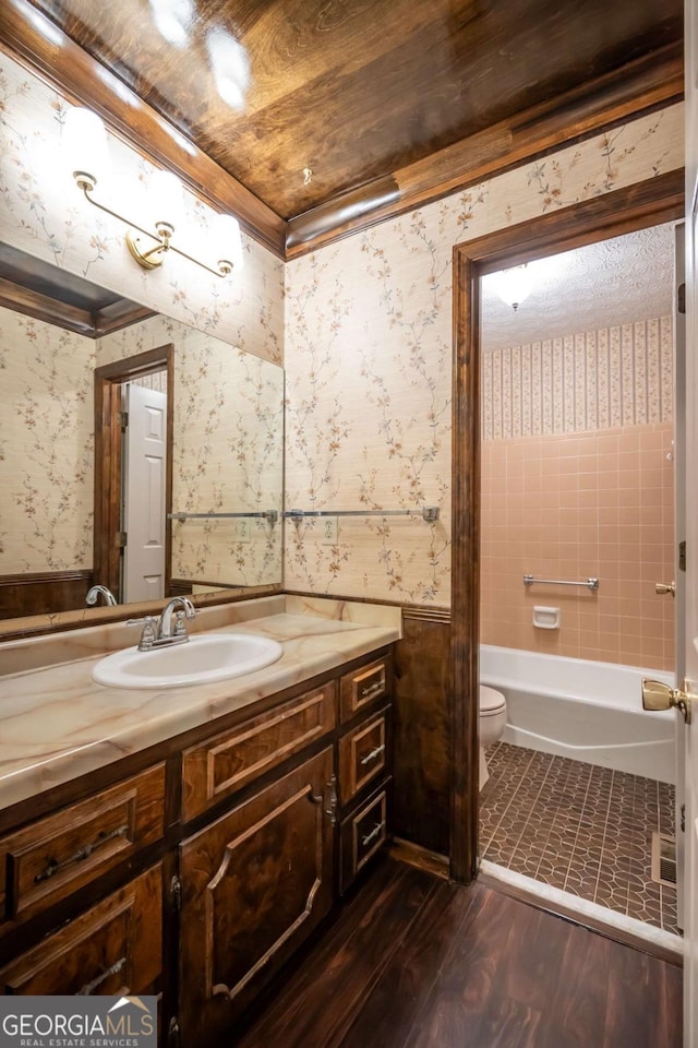 full bathroom with vanity, hardwood / wood-style flooring, tiled shower / bath combo, and toilet