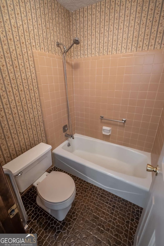 bathroom featuring tile patterned flooring, tiled shower / bath, and toilet