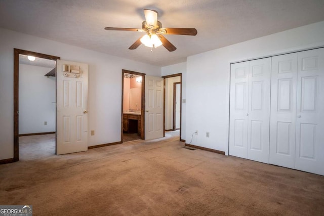 unfurnished bedroom featuring ceiling fan, light colored carpet, ensuite bathroom, and a closet