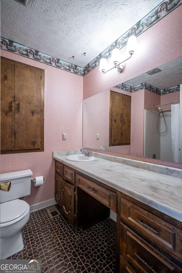 bathroom with vanity, curtained shower, toilet, and a textured ceiling