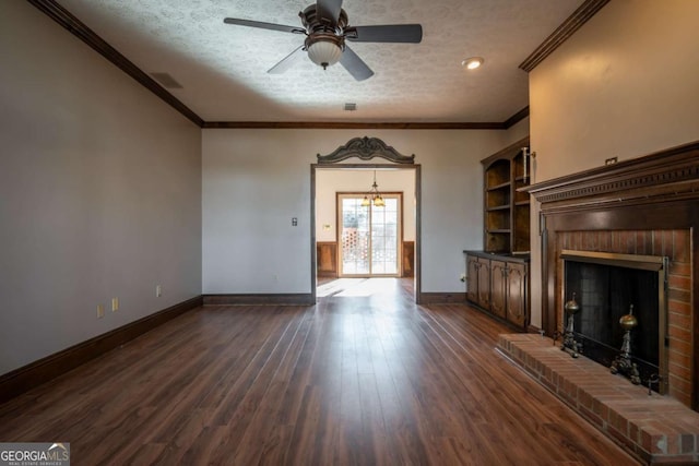 unfurnished living room featuring dark wood-type flooring, a brick fireplace, a textured ceiling, ornamental molding, and ceiling fan