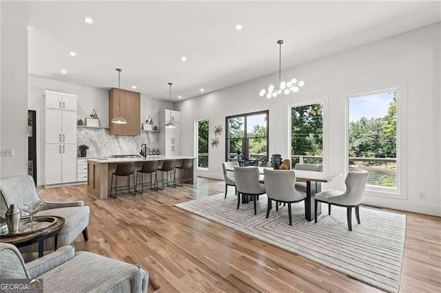 dining room featuring an inviting chandelier, sink, light wood-type flooring, and a wealth of natural light