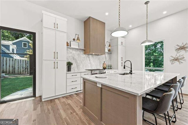 kitchen featuring white cabinetry, sink, and a center island with sink