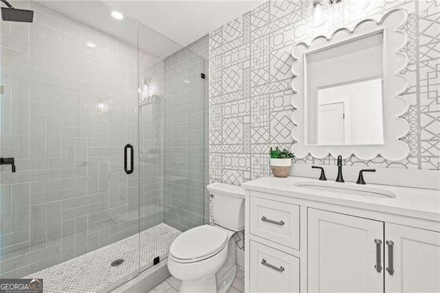 bathroom with vanity, a shower with shower door, tile walls, and toilet