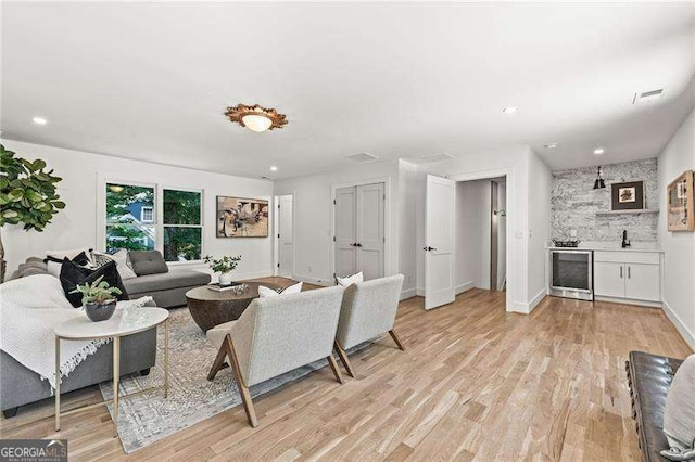 living room with bar and light hardwood / wood-style floors