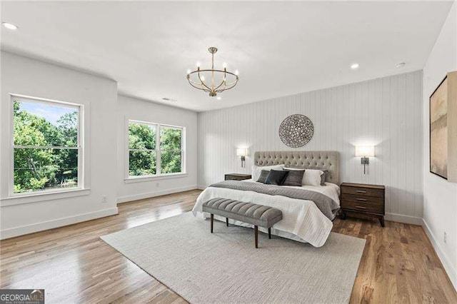 bedroom featuring an inviting chandelier, hardwood / wood-style floors, and multiple windows