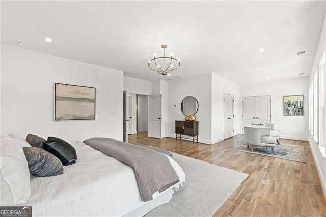 bedroom featuring an inviting chandelier and light hardwood / wood-style flooring