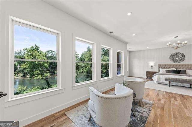 bedroom featuring multiple windows, light hardwood / wood-style floors, and a chandelier