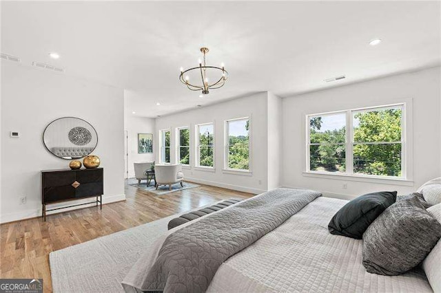 bedroom with light hardwood / wood-style floors, multiple windows, and a notable chandelier