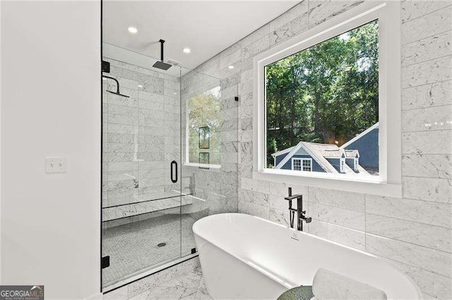 bathroom with tile walls, a healthy amount of sunlight, and separate shower and tub