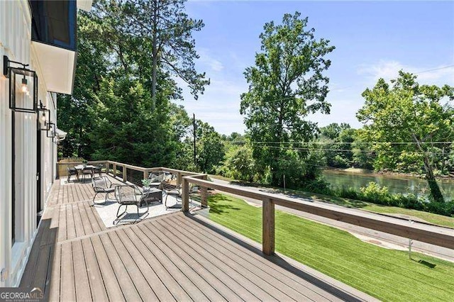 deck with a water view and a lawn