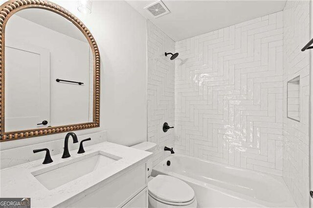 full bathroom featuring tiled shower / bath, vanity, and toilet