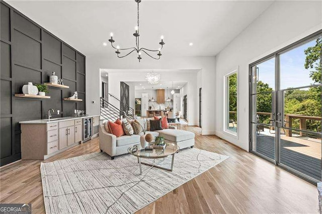 living room featuring wine cooler, a notable chandelier, light hardwood / wood-style flooring, and sink