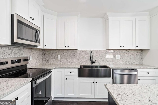 kitchen featuring white cabinetry, appliances with stainless steel finishes, light stone countertops, and sink