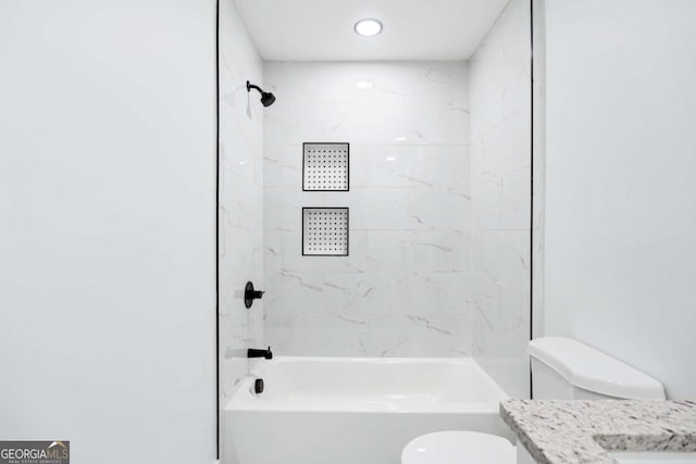 full bathroom featuring tiled shower / bath combo, vanity, and toilet