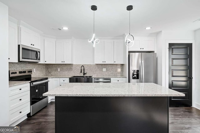 kitchen featuring stainless steel appliances, white cabinetry, a center island, and sink