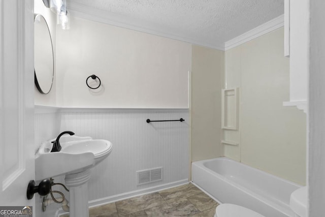 bathroom featuring bathtub / shower combination, ornamental molding, toilet, and a textured ceiling