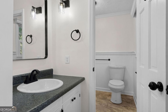 bathroom featuring vanity, ornamental molding, toilet, and a textured ceiling