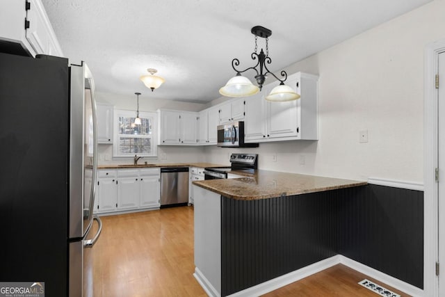 kitchen featuring sink, decorative light fixtures, kitchen peninsula, stainless steel appliances, and white cabinets