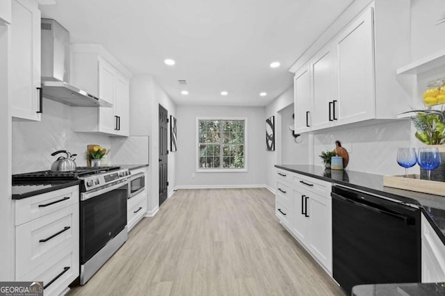 kitchen featuring appliances with stainless steel finishes, tasteful backsplash, white cabinetry, light wood-type flooring, and wall chimney exhaust hood