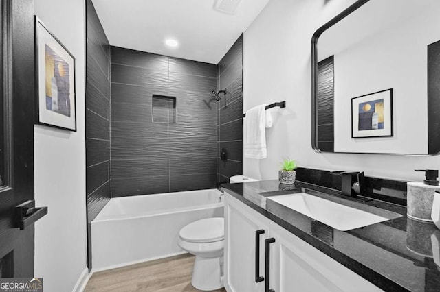 full bathroom with tiled shower / bath combo, wood-type flooring, vanity, and toilet