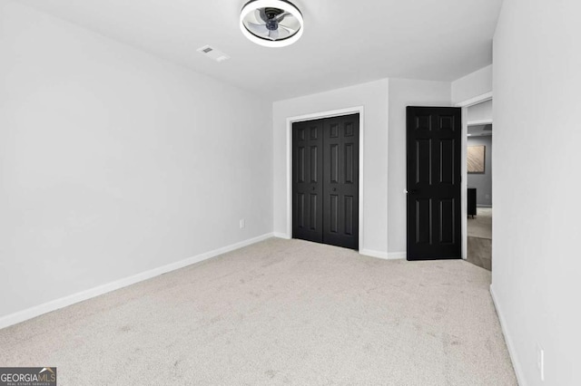 unfurnished bedroom with light carpet and a closet