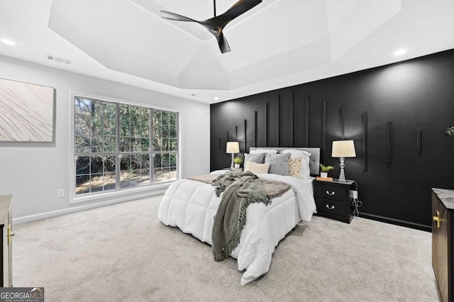 bedroom with light carpet, a tray ceiling, and ceiling fan